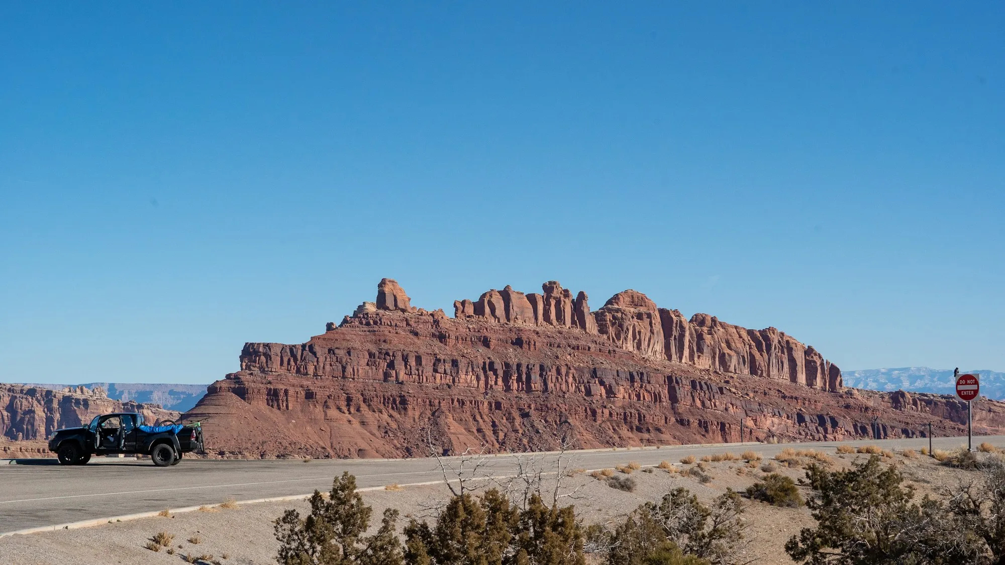 A two-lane road running past red rock buttes in the Utah desert