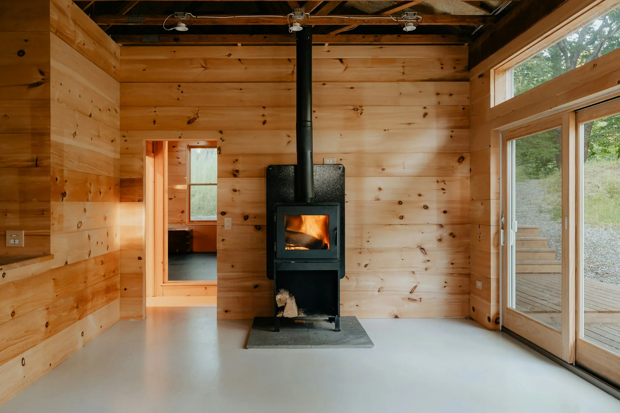 A wood stove burning inside a pine-paneled cabin