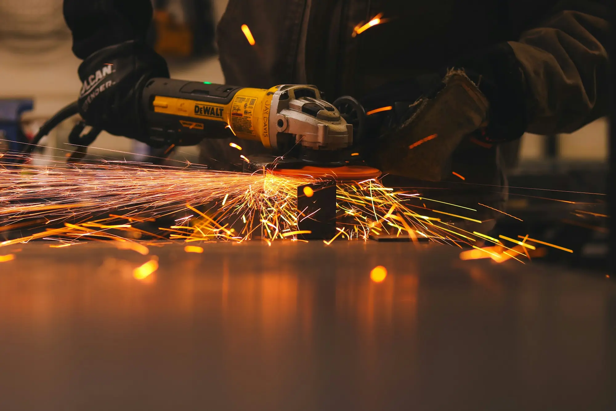 Sparks flying as a worker cuts sheet metal with an angle grinder